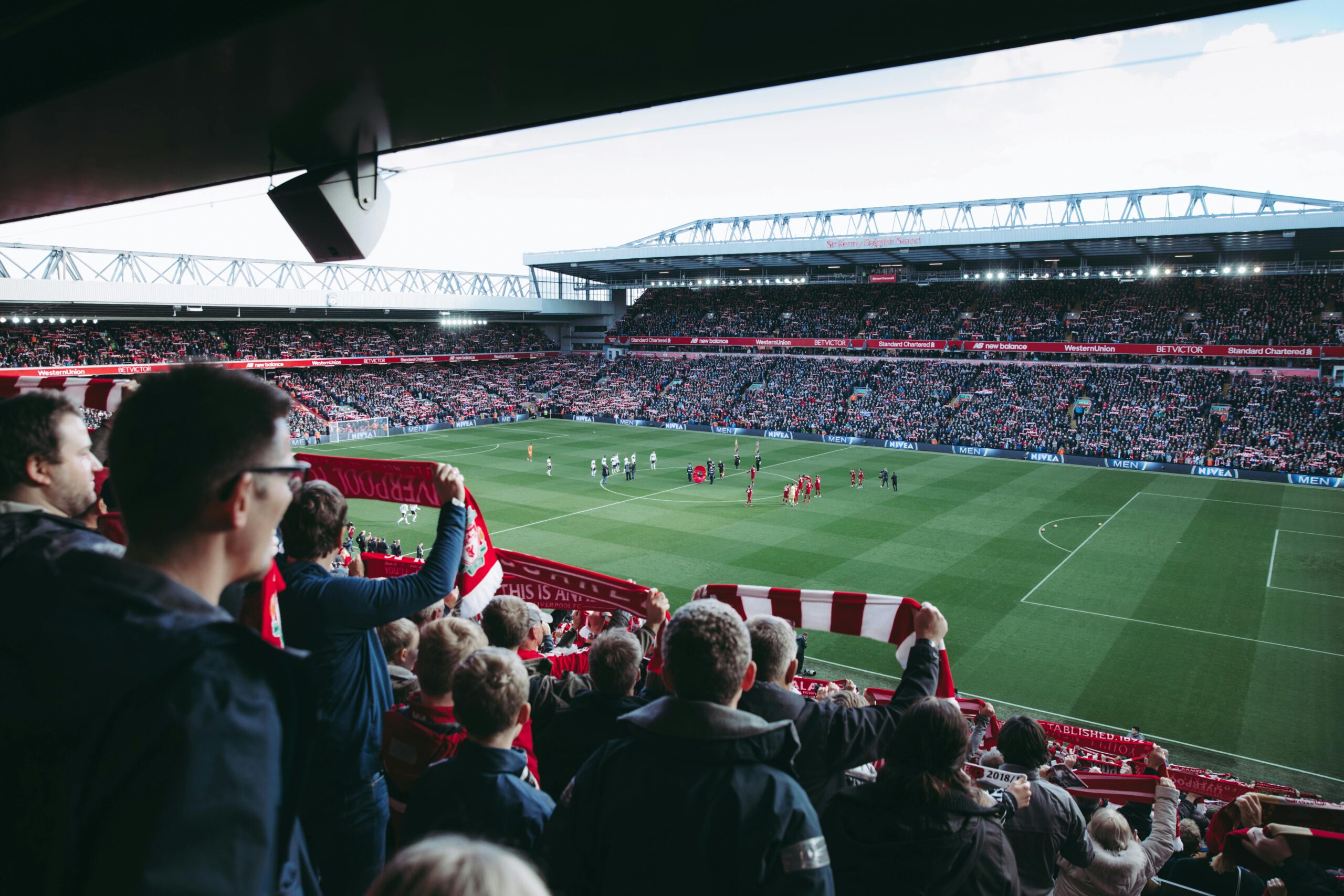 Home Fans cheer as players take the field at a vibrant football stadium, creating an electric atmosphere.