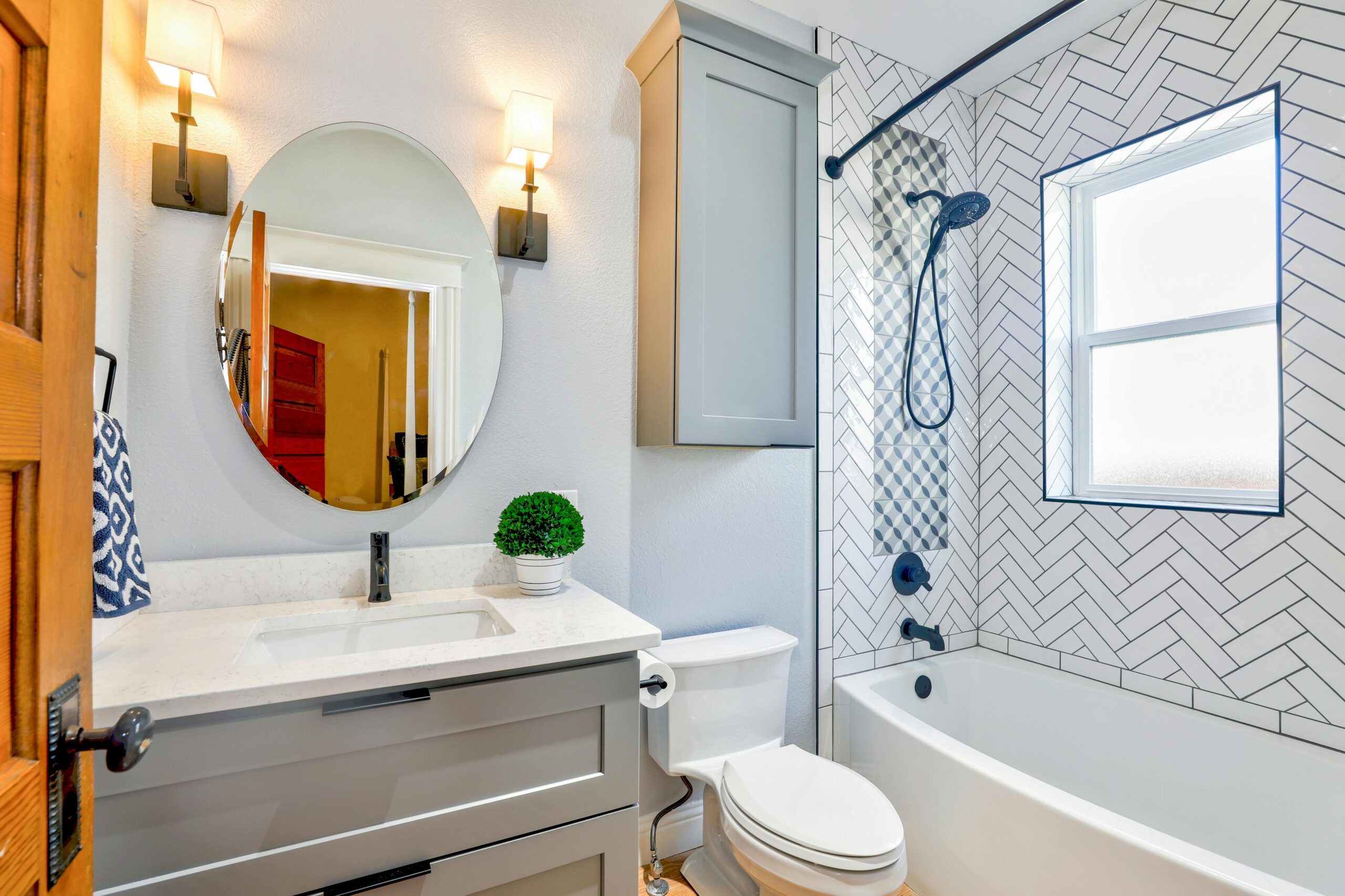Home Elegant modern bathroom featuring chevron tiles, oval mirror, and sleek fixtures for a contemporary look.