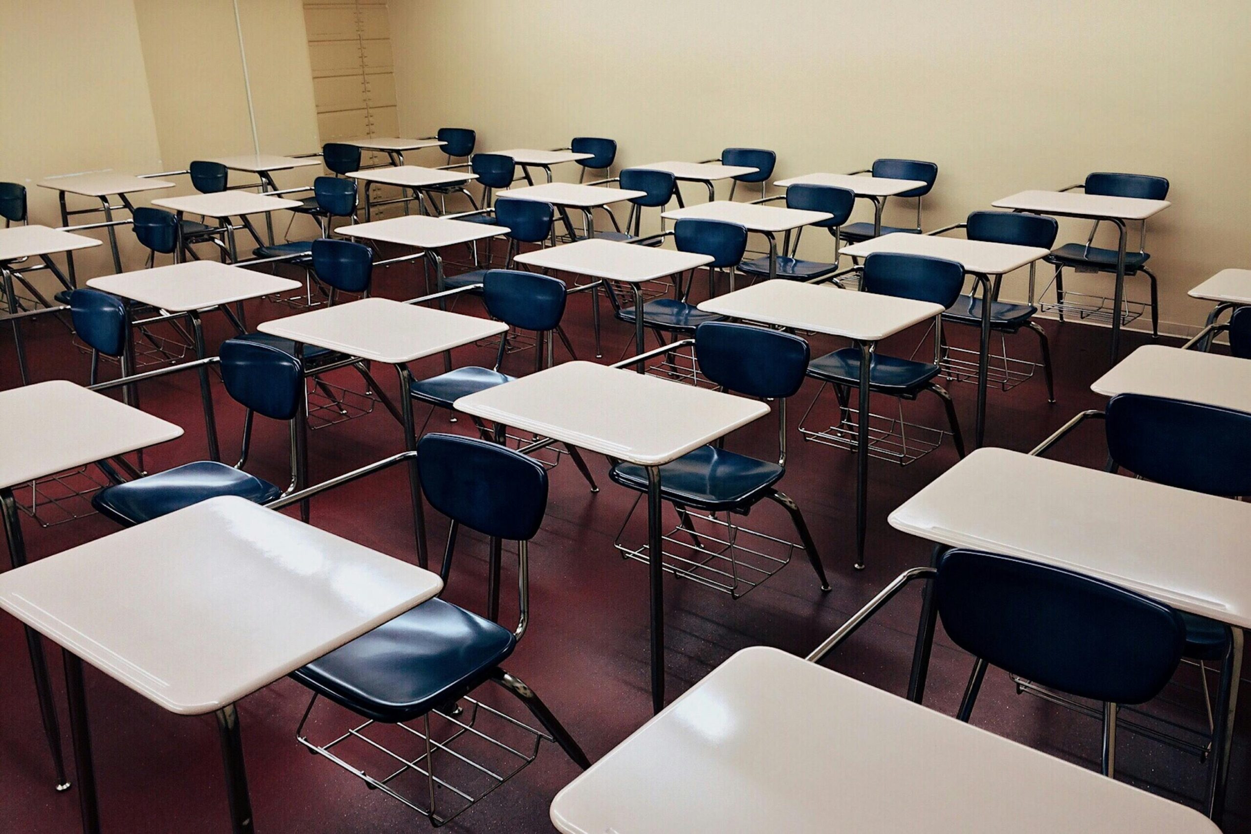 Home An indoor view of a modern, clean classroom with rows of empty desks and chairs.