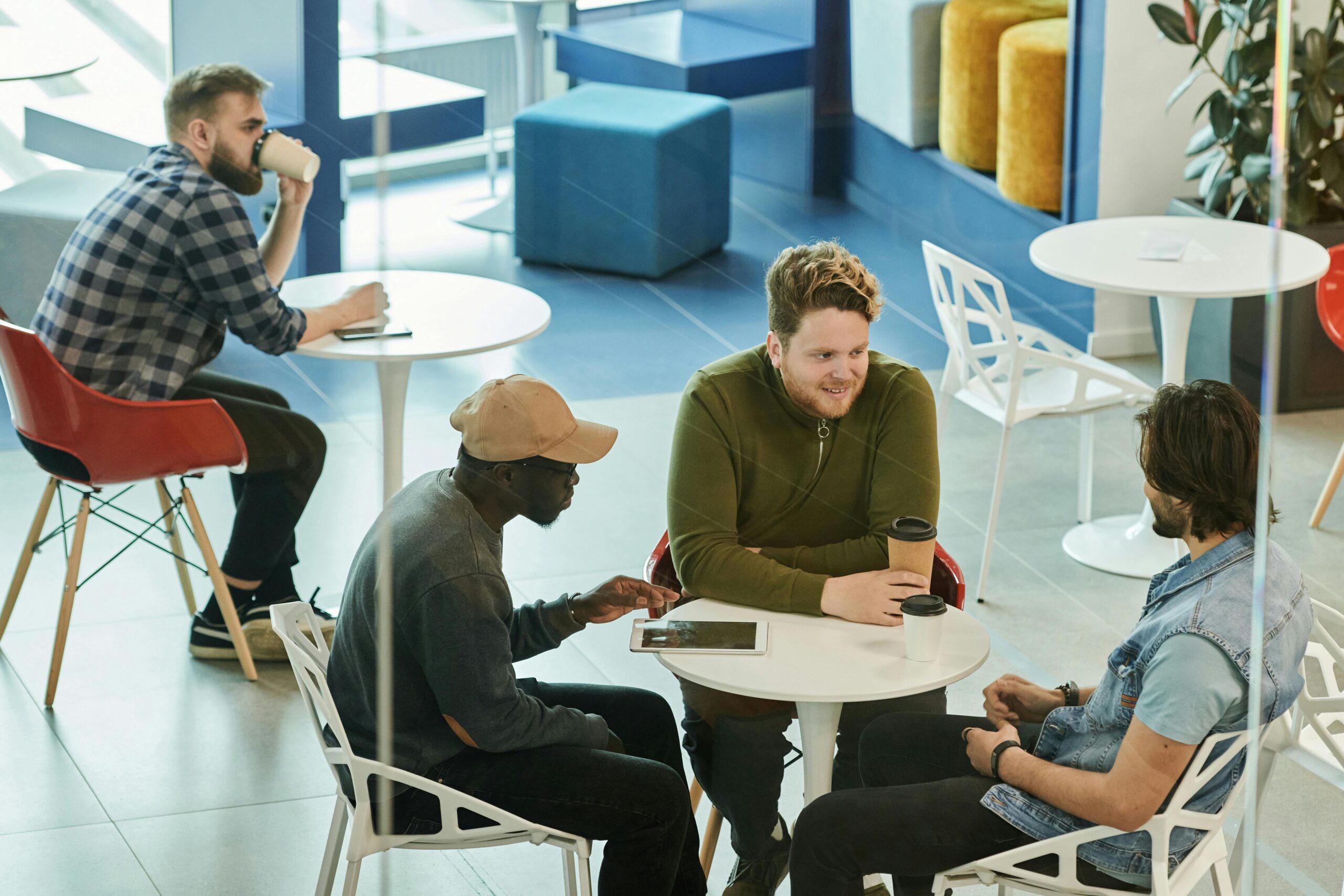 Home Diverse group of men enjoying coffee and conversation in a modern café setting.